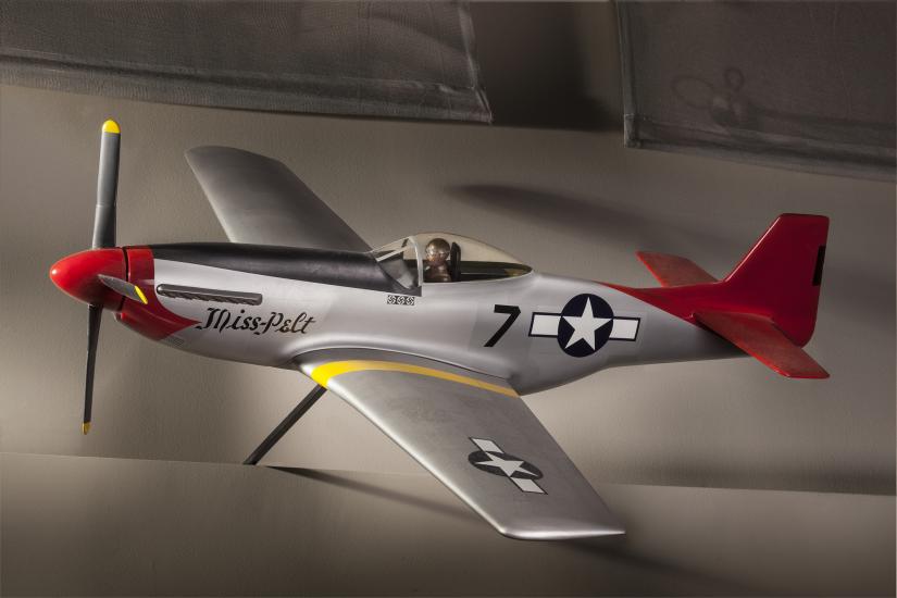 Side view of silver-colored monoplane model aircraft with one engine and a red tail and nose. Blue and white star emblem is painted on the rear of the fuselage and on the left wing.