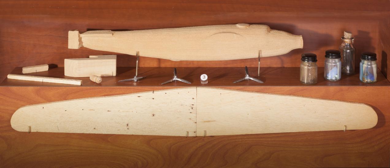 Parts and pieces of an uncomplete monoplane model kit made from solid wood.