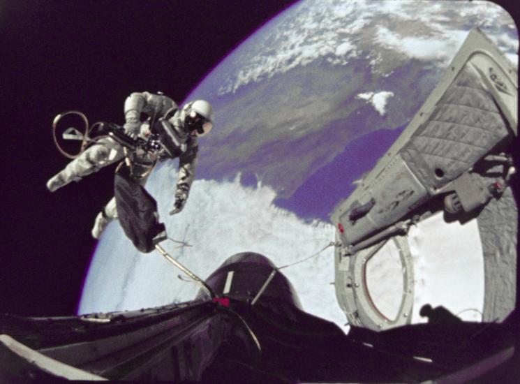 Edward White, a male astronaut, performs a spacewalk while tethered to the Gemini 4 spacecraft.