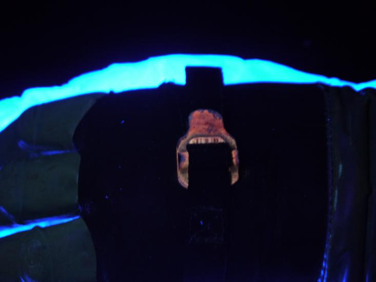 Special ultraviolet light reveals the metal on a buckle (seen as a red and black color) of a glove is corroding.