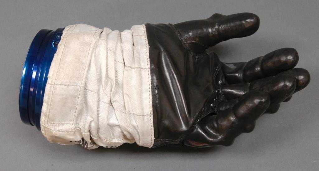 Left glove to astronaut suit. Black-colored rubber palm and fingertips section attached to a white fabric. The white fabric is attached to a solid blue disconnect from the rest of the suit.