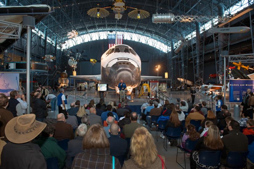 Museum visitors listen to a presentation in the Space Hangar of the Steven F. Udvar-Hazy Center during an open house event.