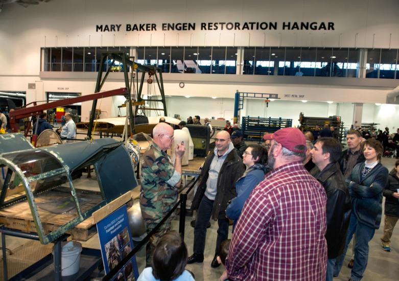 Museum specialists give a presentation to visitors inside the Museum's restoration hangar.