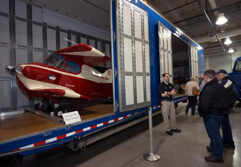 A Museum staff member provides visitors a lesson on artifact transport in front of a partially open storage unit.