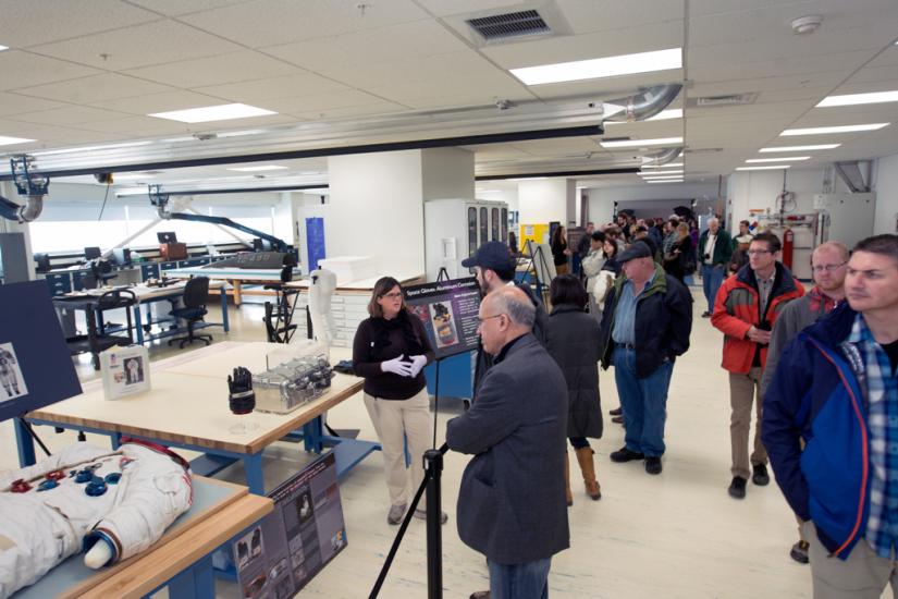 A member of the Museum's conservation staff presents work they have done to conserve objects to many visitors inside the Museum's conservation laboratory.