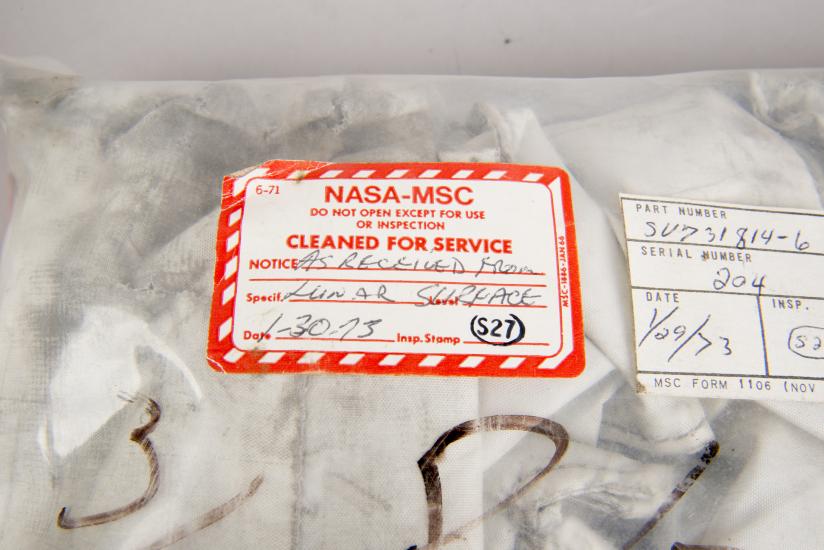 Cover of a sealed white-colored fabric cover for an oxygen purge system. One red and white tag states that the cover has been "cleaned for service" and is not to be opened "except for use or inspection".