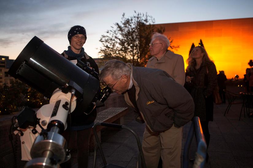 Museum staff assist in allowing visitors to use telescopes at a Museum event.