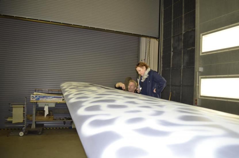 A Museum specialist and a Museum curator discuss the finished paint job on a silver-colored aircraft undergoing the restoration process.