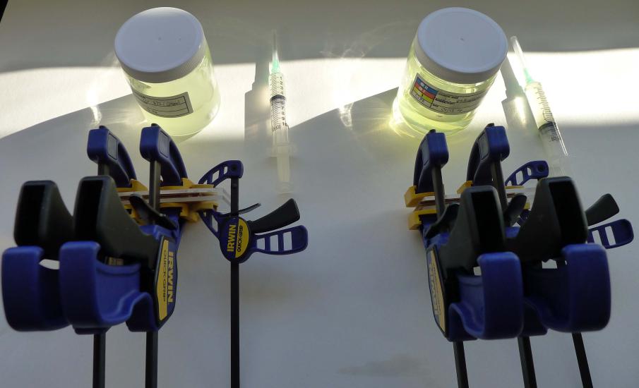 A pair of tool sets used to perform resin consolidation experiments. The tools include a syringe, a jar of a yellow transparent object, and a large blue, black, and yellow object.