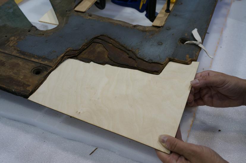 A Museum staff member holds a thin layer of plywood to be used on holes in a World War II era aircraft.