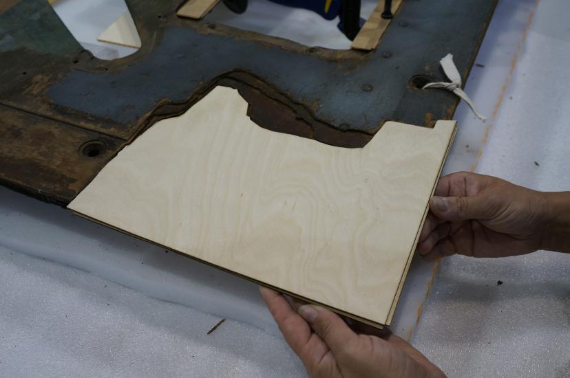 A Museum staff member places a third layer of plywood intended for use in repairing holes in a World War II era aircraft.