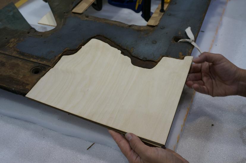 A Museum staff member places a fourth layer of plywood intended for use in repairing holes in a World War II era aircraft.