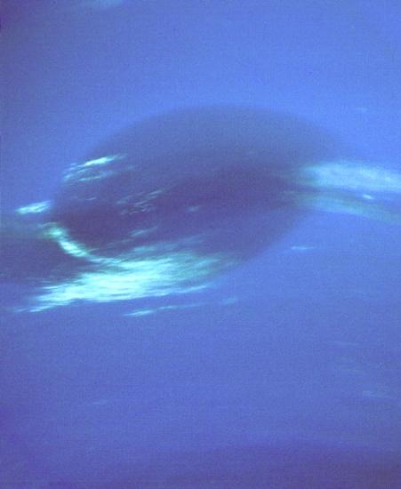 A view of Neptune's Great Dark Spot, a darker blue area of Neptune with light blue wisps near the bottom and the sides.