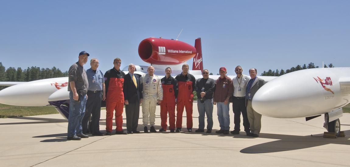 A group of eleven people stand in front of a red and white aircraft at the Udvar-Hazy Center.