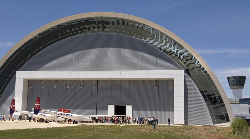 A white and red aircraft stands in front of a set of doors in the collections storage area of the Udvar-Hazy Center.