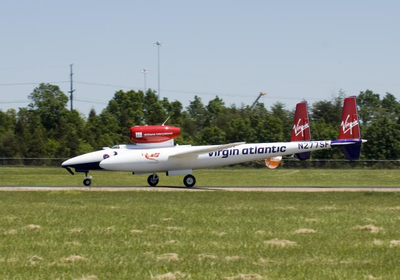 A white and red aircraft lands on a tarmac near the Udvar-Hazy Center.