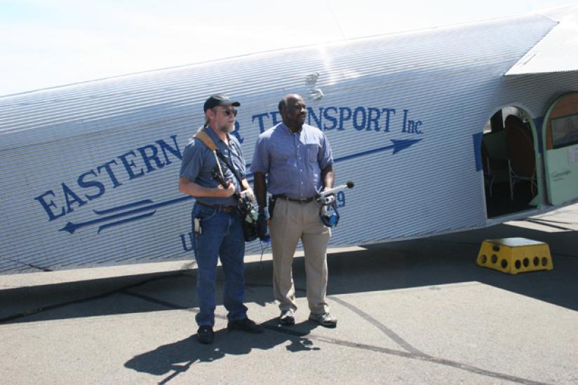 Two Smithsonian employees stand in front of white Ford Tri-Motor aircraft.