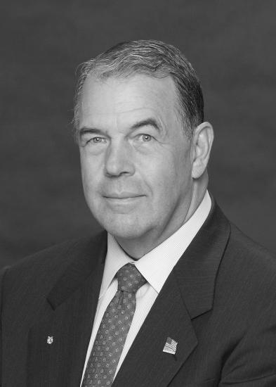 Black and white portrait of David C. Hurley, a former president of the National Air and Space Museum Board, who smiles towards the subject