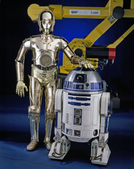 R2-D2, a blue and white robot "droid" from the Star Wars franchise, and C-3PO, a golden-metalic robot "droid" from the Star Wars franchise, stand next to each other on display at the museum.