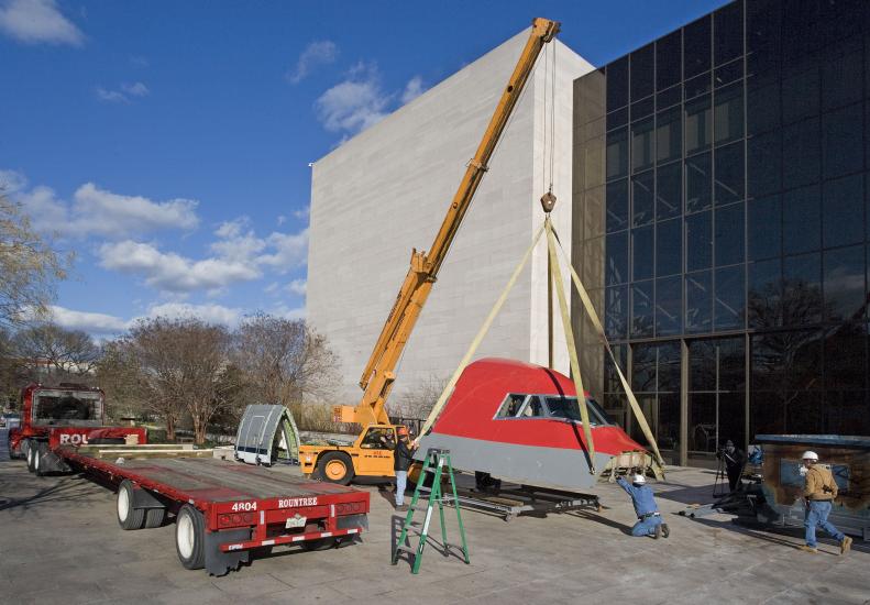 Museum employees begin to lift the Boeing 147 outside of the flagship museum building prior to installation inside the building.