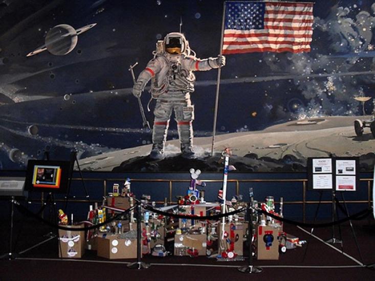 A finished view of a space station project completed by museum patrons below a mural of a man on the moon.