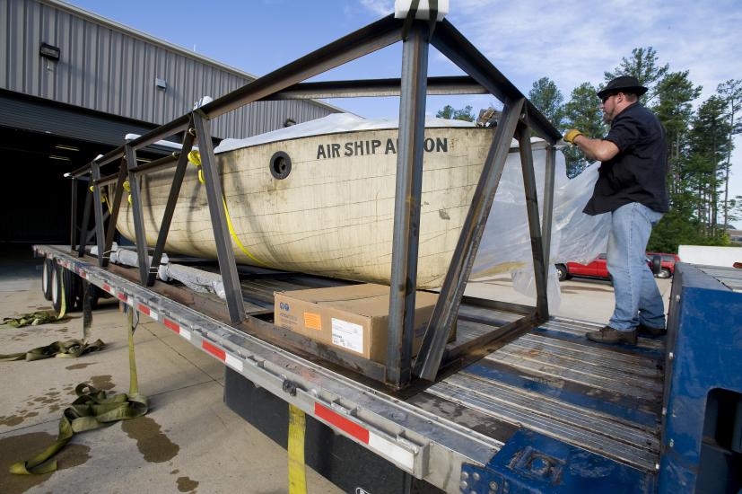 A wooden lifeboat sits on the back section of a vehicle