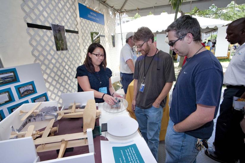 A woman displays an exhibit to patrons at the Folklife Festival.