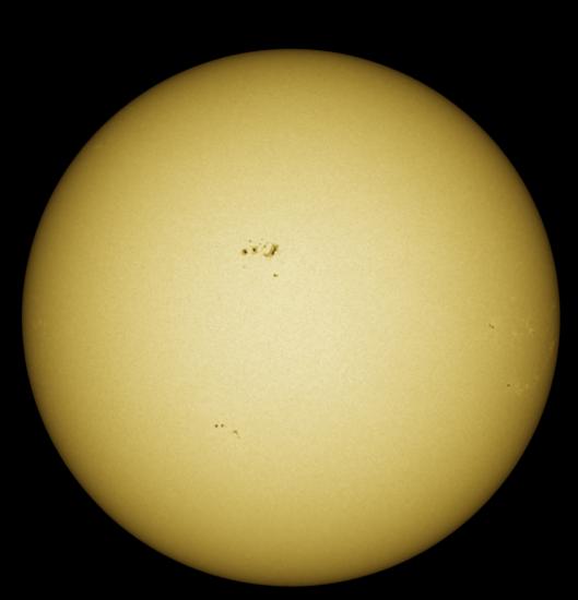 Disk view of the Sun with visible sunspot groups near the center of the Sun's visible surface.