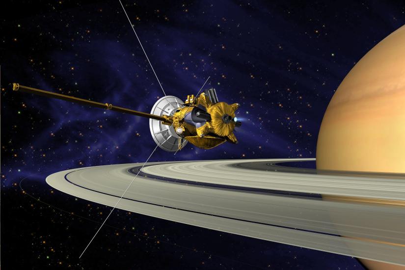 An artist's vision of the Cassini spacecraft, a yellow and white spacecraft with long probes, prepares to enter Saturn's orbit.