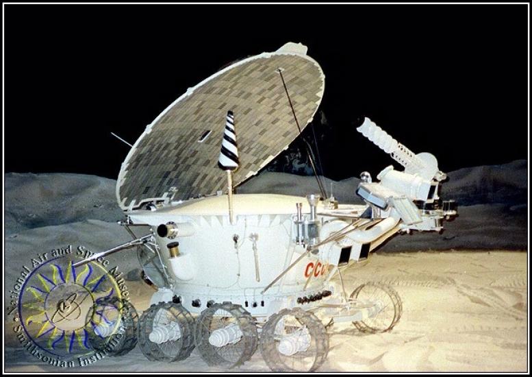 A white robotic spacecraft with a oblong-shaped base. A circular solar panel and multiple probes and cameras are attached to the base.