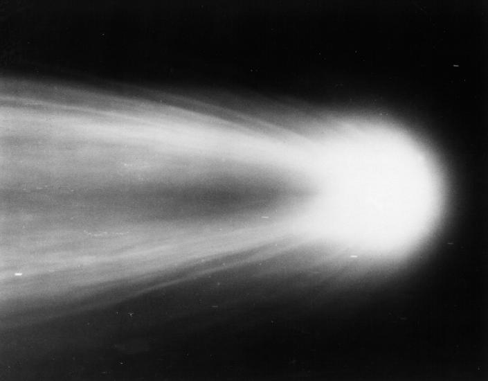 Close-up view of Halley's Comet as it leaves a meteor trail in the sky behind it.