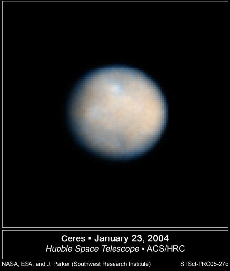 A round-shaped, gray and tan asteroid with multiple visible craters.