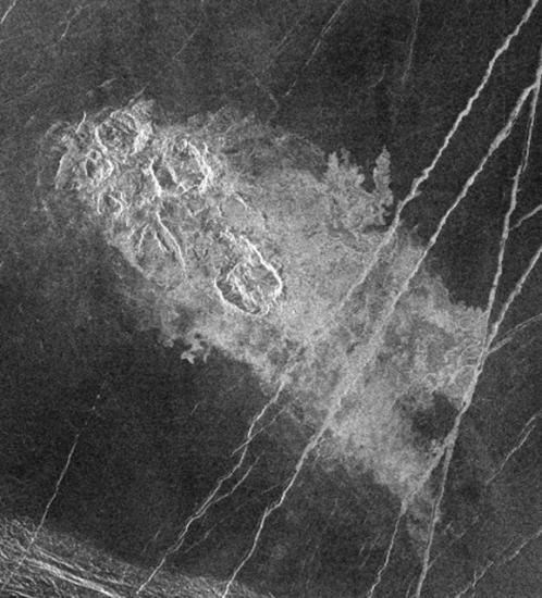 A satellite view of a set of impact craters on the surface of Venus, which looks lighter in color compared to the other sections visible.