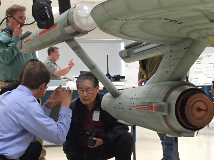 Multiple Museum staff members in charge of a gray spaceship studio model from the series Star Trek tour the Museum's conservation laboratory, where the studio model is undergoing conservation treatments.