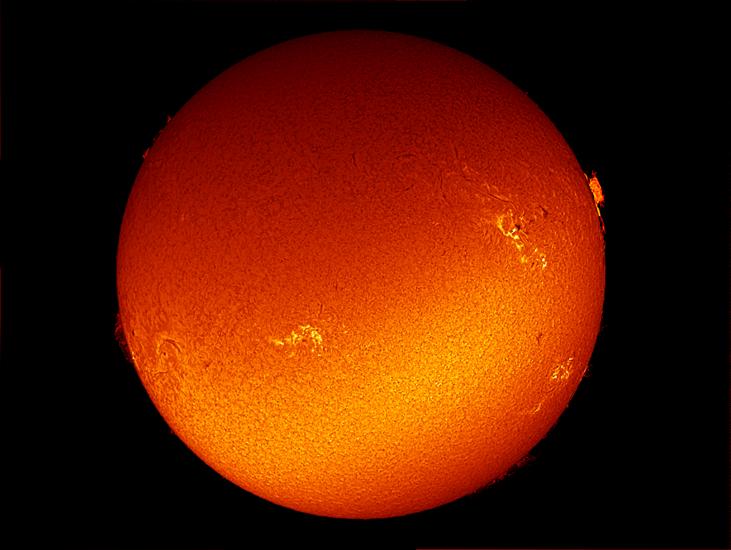 Disk view of the Sun with multiple sunspot clusters, individual sunsplots, and prominences of plasma floating above the Sun's surface.