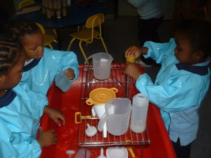 Preschoolers play at a water table. 