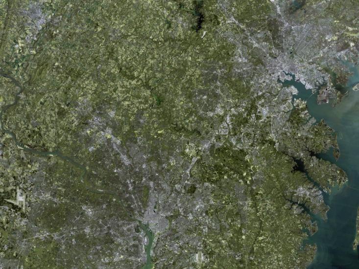 A satellite view of the Washington, D.C. and Baltimore, Maryland areas. Much green can be seen but the two cities are also visible.