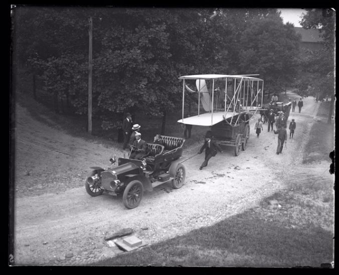 Historic photo of early biplane being transported