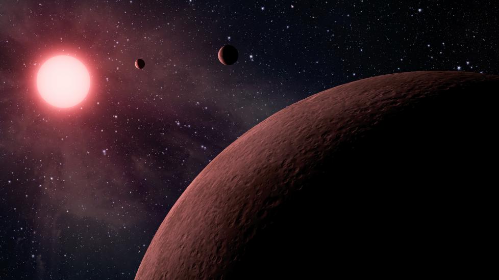 Depiction of three small terrestial planets in orbit close to a star in a far away solar system.