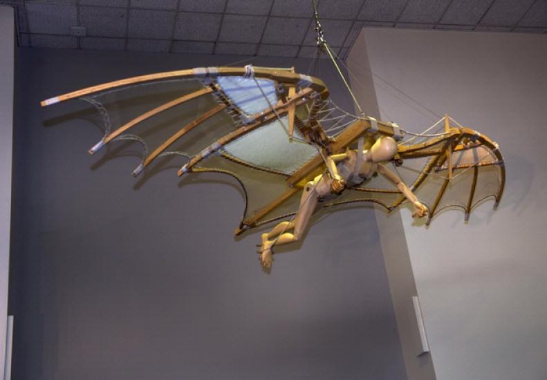 A wooden glider model hanging in the museum. The wings are shaped like a bat.