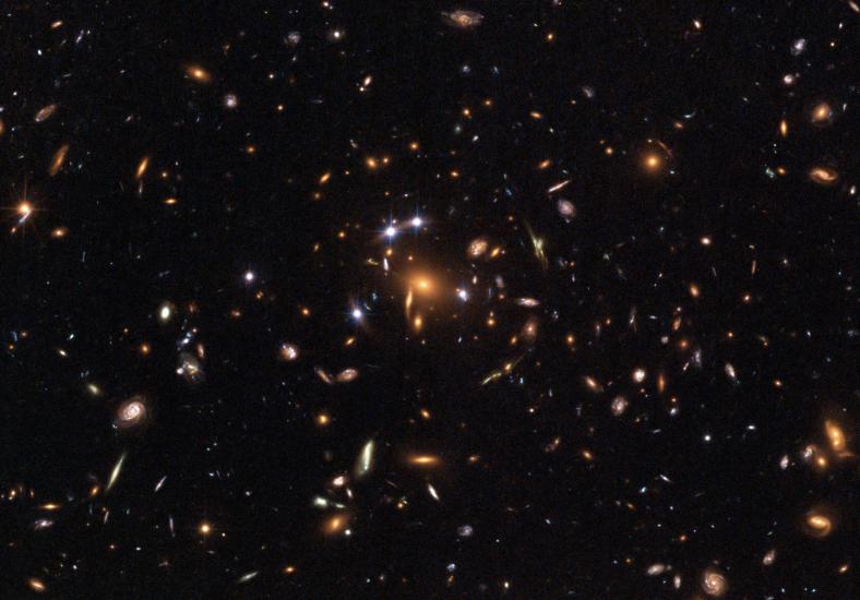 A telescope view of many stars, including a large light in the center of the image that looks like a star but is actually light reflecting from a quasar.