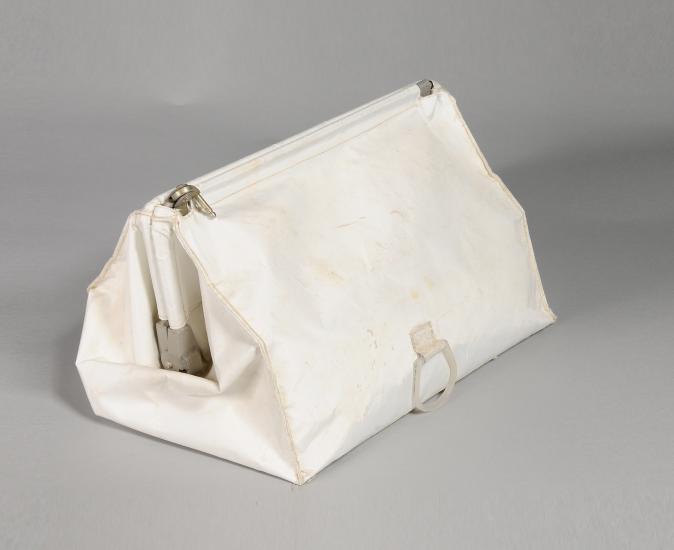 White cloth stowage bag used during Apollo 11 mission. Bag has one zipper entry at the top of the bag.