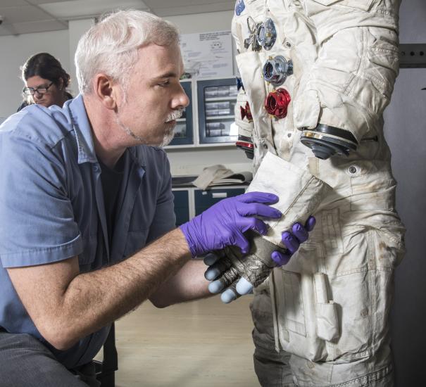 Exhibits Specialist Adam Bradshaw with the white beta cloth lunar spacesuit 