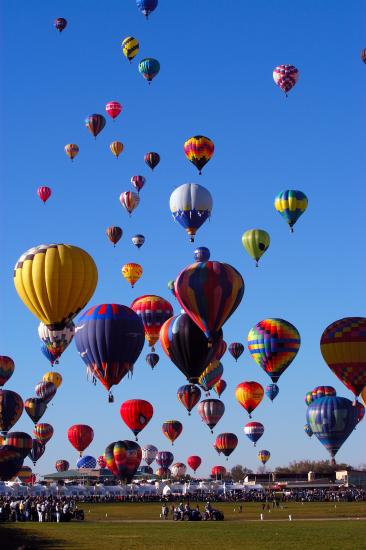 Many multicolored balloons float in the air.