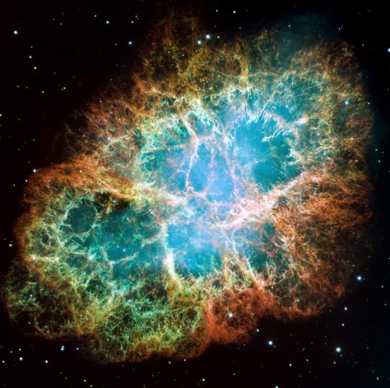 An image taken by a space telescope and colorized by scientists and artists, this gives us a picture of the cosmos. The edges are black with white glowing dots that appear as stars. In the center is the crab nebula, an organic circular shape that opens like a wound or a rip in the the black starry field. There are spindly formations that stretch towards the center of the opening, layers and layers deep, like vines. The opening is mostly shades of blue and green, with some orange around the edge.