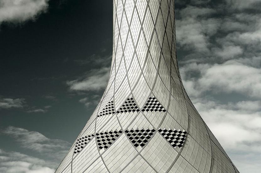 Partial view of white, conical shaped air control tower. The exterior features a tiled pattern throughout.