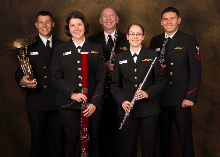 A group of five U.S. Navy musicians pose together formally. Each musician is holding a woodwind instrument.