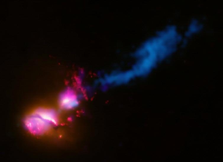 A black hole from the center of one galaxy reaches the edge of a neighboring galaxy.