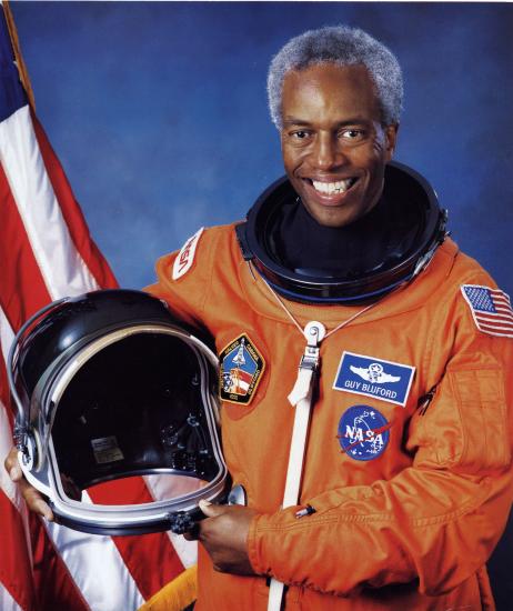 Guion Bluford, an African-American male astronaut, poses formally in an astronaut suit with his helmet.