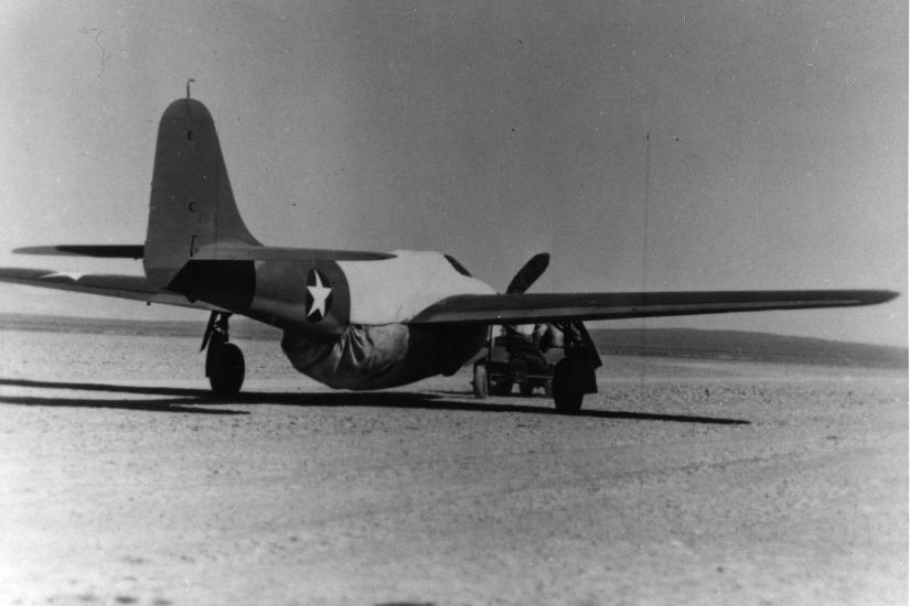 Rear view of an early jet aircraft with an additional proppelor added to an engine to disguise the aircraft.